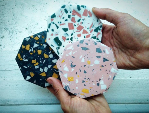 An image of hands holding three coasters 